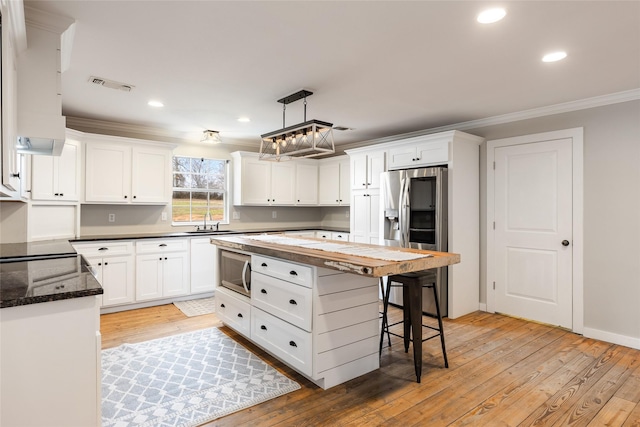 kitchen featuring stainless steel appliances, a sink, visible vents, and white cabinets