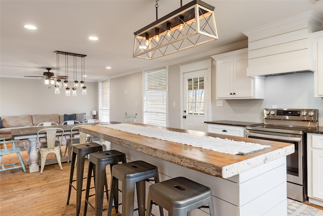 kitchen with decorative light fixtures, white cabinets, stainless steel electric range oven, and wood counters