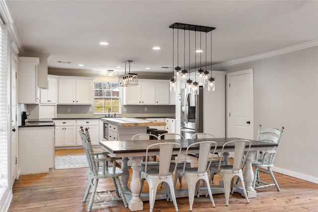 dining room with baseboards, ornamental molding, recessed lighting, and light wood-style floors