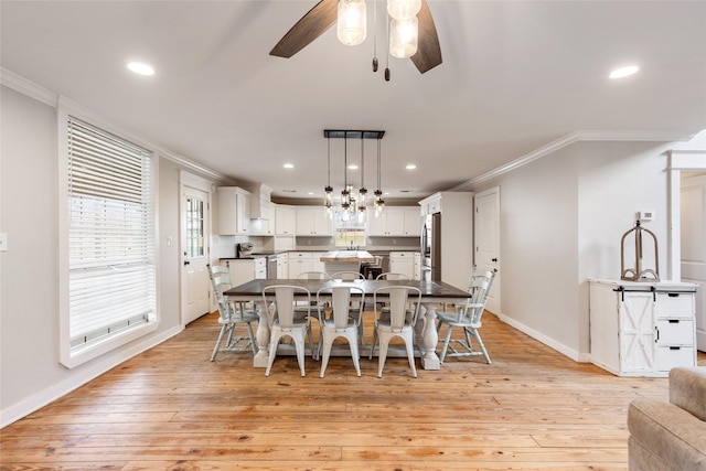 dining room featuring ornamental molding, light wood-style floors, and a ceiling fan