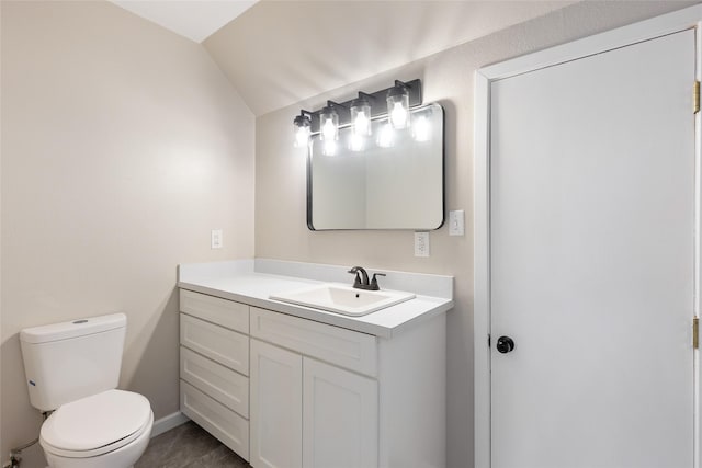 half bath with toilet, vaulted ceiling, and vanity