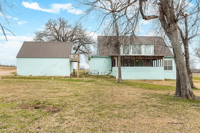 rear view of property with metal roof and a yard