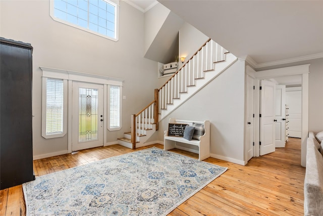 foyer with ornamental molding, a wealth of natural light, wood finished floors, and stairs