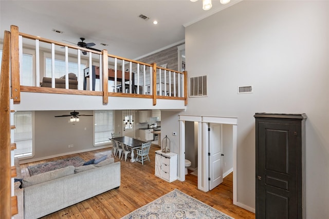 living room with a towering ceiling, light wood finished floors, and visible vents