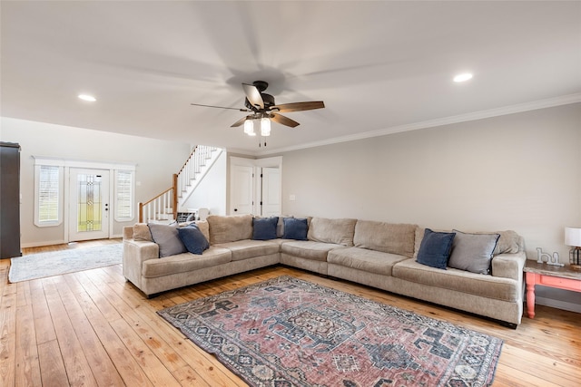 living room with ceiling fan, light wood finished floors, stairway, and crown molding