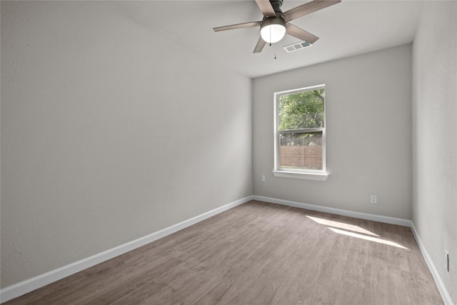 empty room with ceiling fan, wood finished floors, visible vents, and baseboards