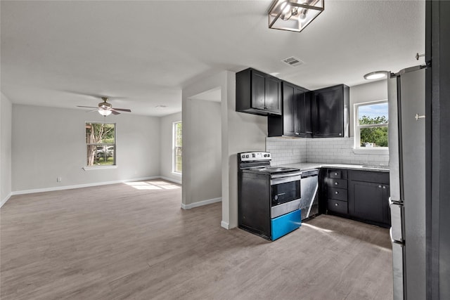 kitchen featuring dark cabinets, visible vents, open floor plan, appliances with stainless steel finishes, and backsplash