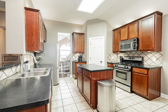 kitchen with light tile patterned floors, stainless steel appliances, lofted ceiling, backsplash, and a sink