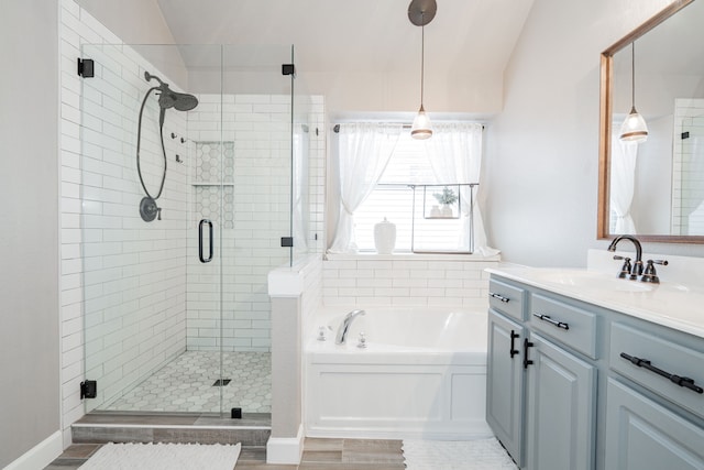 bathroom featuring vaulted ceiling, vanity, a shower stall, and a bath