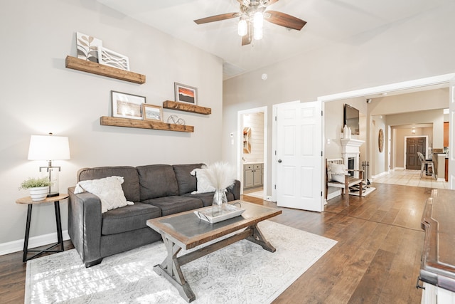 living area featuring a ceiling fan, baseboards, and hardwood / wood-style flooring