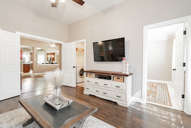 living area featuring washer / clothes dryer, dark wood-style flooring, ceiling fan, and baseboards