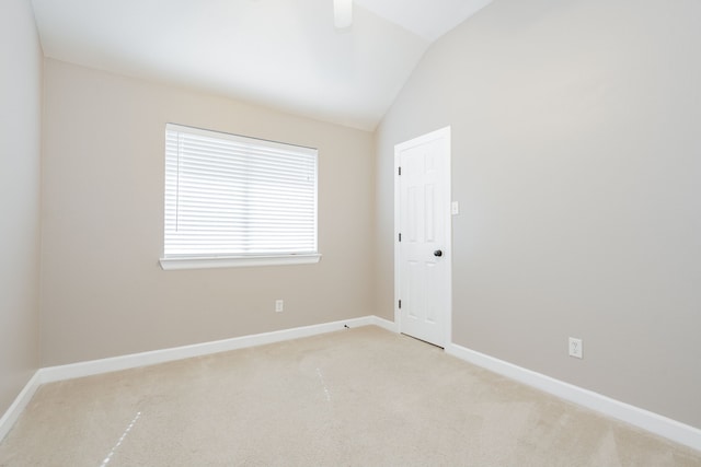 empty room with light carpet, vaulted ceiling, and baseboards