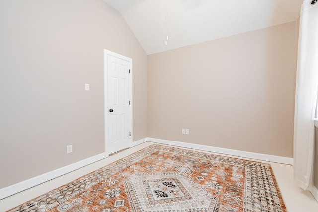 spare room featuring vaulted ceiling and baseboards