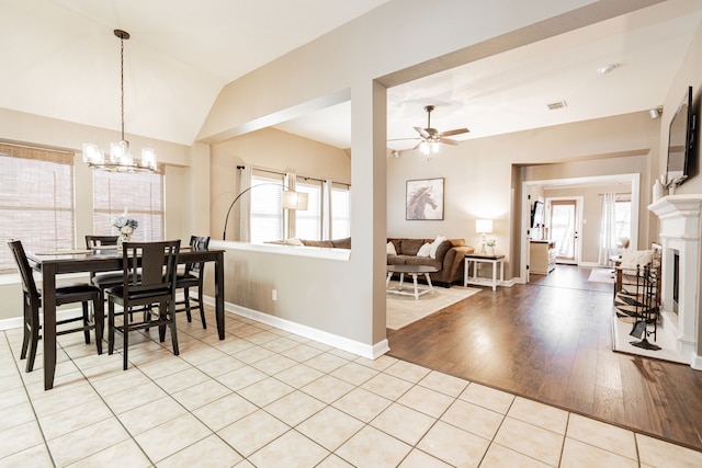 dining area featuring visible vents, light wood-style flooring, vaulted ceiling, baseboards, and ceiling fan with notable chandelier