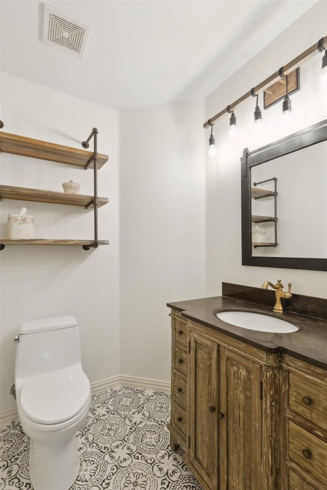 half bathroom with toilet, baseboards, visible vents, and vanity