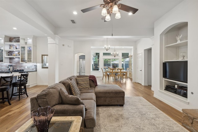 living room featuring visible vents, arched walkways, ceiling fan with notable chandelier, recessed lighting, and light wood-style flooring