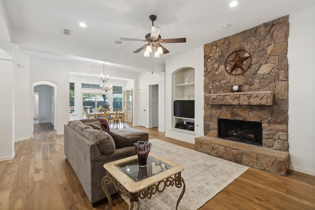 living area featuring baseboards, built in features, ceiling fan with notable chandelier, and wood finished floors