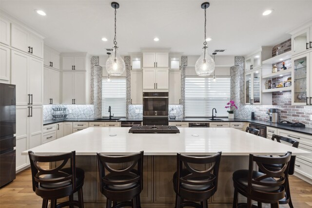 kitchen featuring a sink, a breakfast bar area, double wall oven, tasteful backsplash, and visible vents