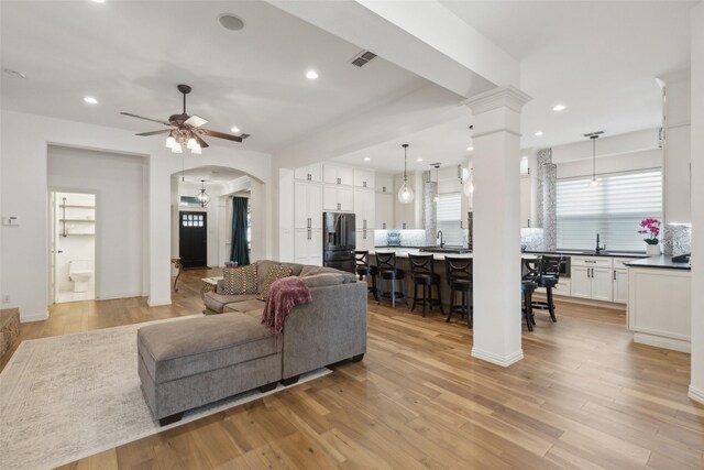 living room featuring recessed lighting, arched walkways, ceiling fan with notable chandelier, and light wood finished floors