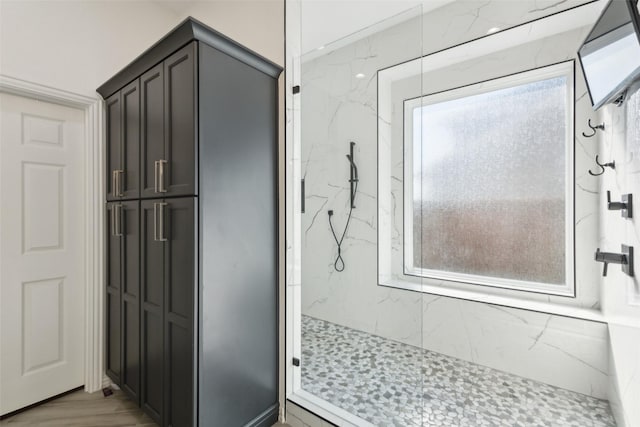 full bath with plenty of natural light and a marble finish shower