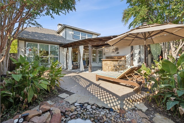 back of property with ceiling fan, fence, an outdoor bar, area for grilling, and a patio area