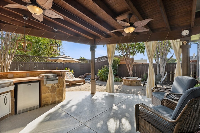 view of patio / terrace featuring area for grilling, a ceiling fan, a fenced backyard, and an outdoor fire pit