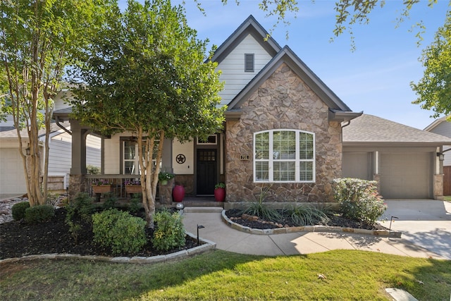 view of front of house featuring covered porch, a front yard, a garage, concrete driveway, and stone siding