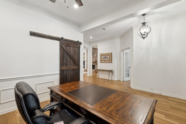 home office featuring a ceiling fan, crown molding, a barn door, baseboards, and light wood-style flooring