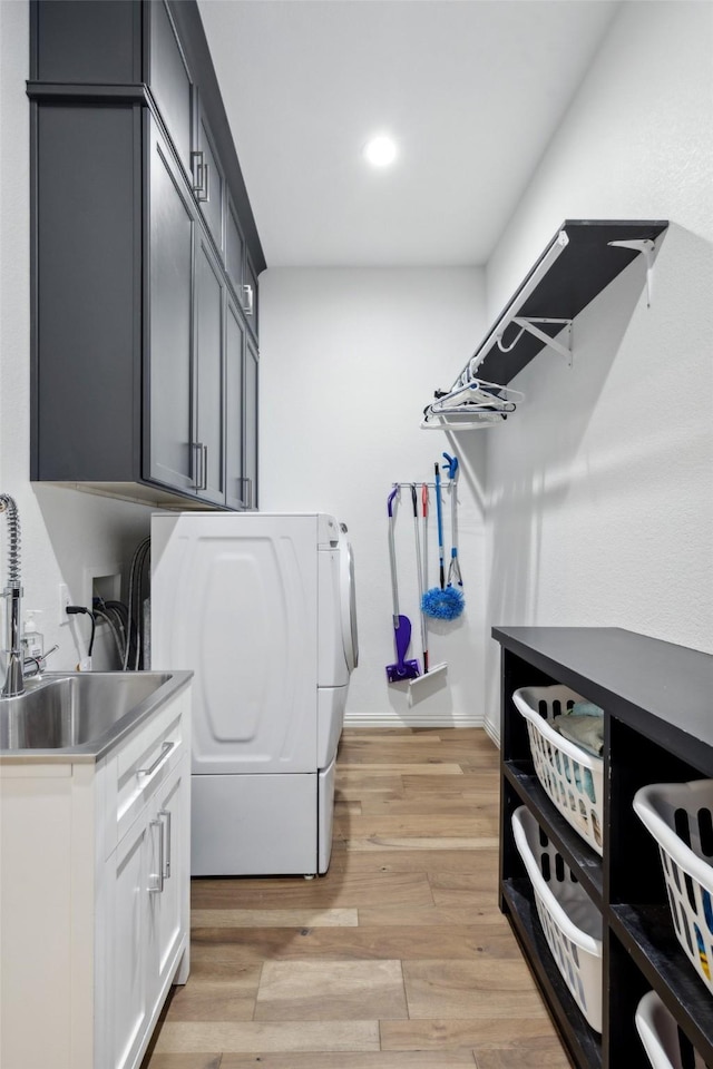 washroom featuring washing machine and dryer, light wood-type flooring, cabinet space, a sink, and recessed lighting