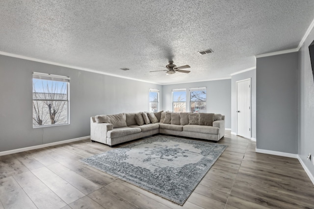 living room with baseboards, wood finished floors, visible vents, and crown molding