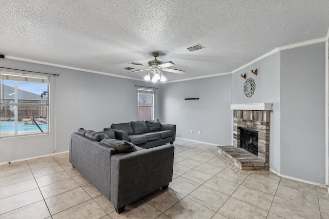 living room featuring visible vents, a ceiling fan, ornamental molding, a brick fireplace, and light tile patterned flooring