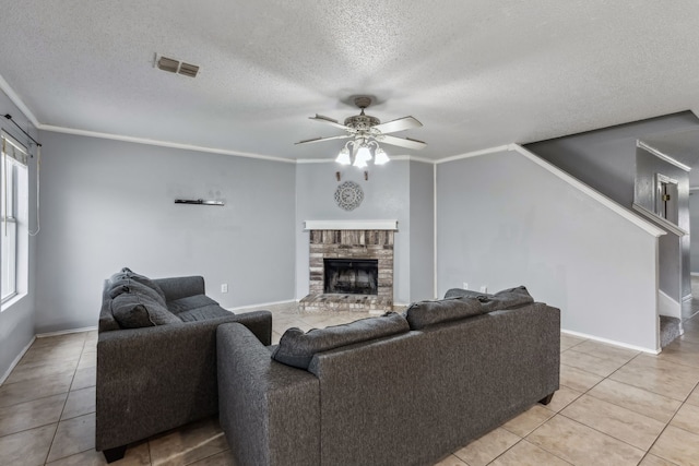 living area featuring light tile patterned floors, ceiling fan, a fireplace, visible vents, and ornamental molding