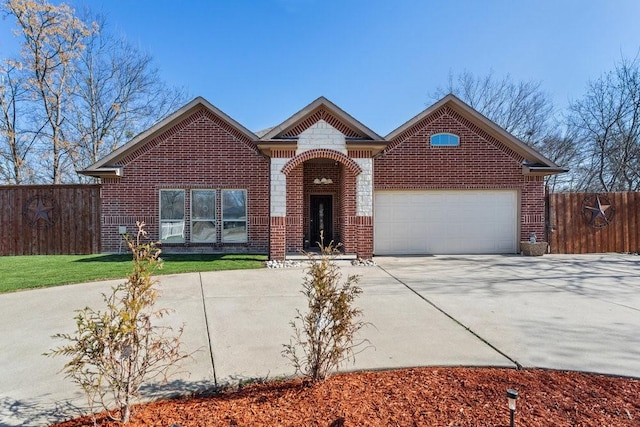 traditional home featuring driveway, brick siding, an attached garage, and fence