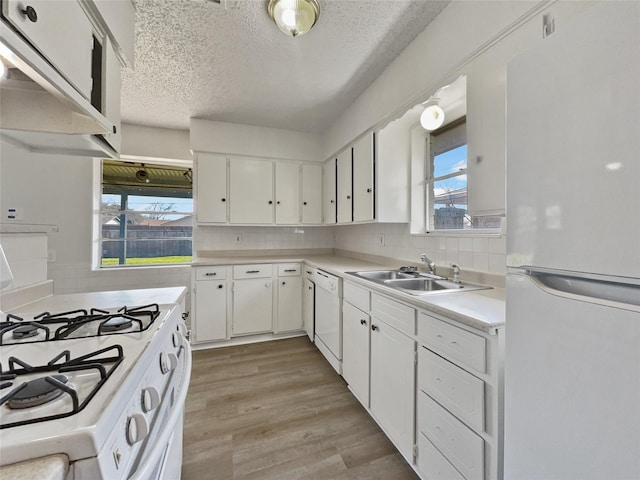 kitchen with light countertops, white appliances, a sink, and white cabinetry