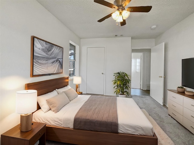 bedroom featuring visible vents, ceiling fan, a textured ceiling, and carpet flooring