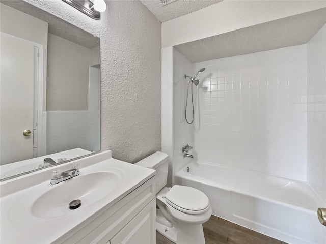 bathroom featuring a textured ceiling, a textured wall, toilet, shower / bath combination, and vanity