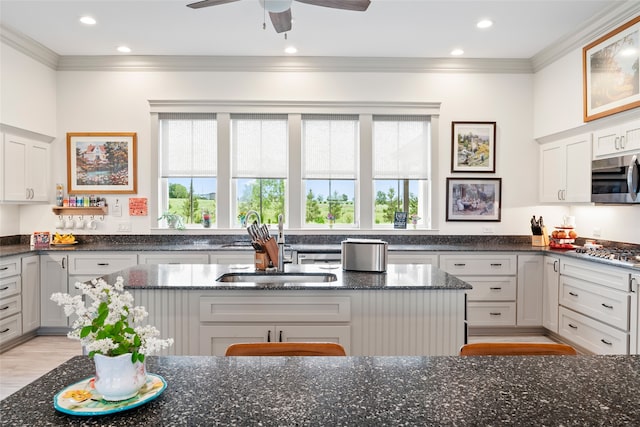 kitchen featuring stainless steel appliances, plenty of natural light, dark stone counters, and ornamental molding