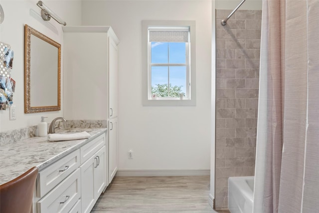 full bath with baseboards, shower / bath combo with shower curtain, wood finished floors, and vanity