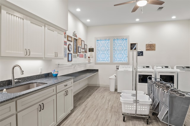 kitchen with visible vents, dark stone countertops, washing machine and clothes dryer, light wood-type flooring, and a sink