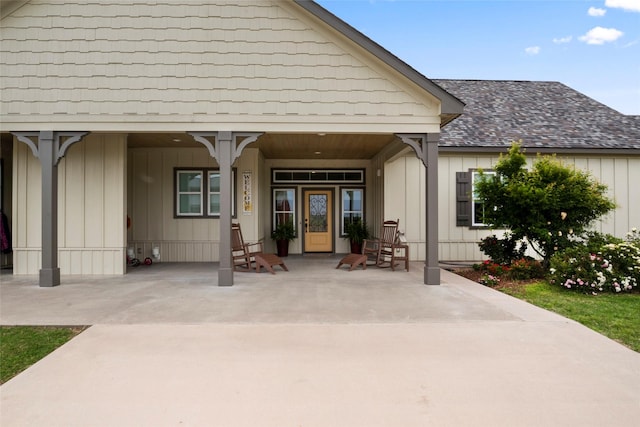 doorway to property with board and batten siding, roof with shingles, and a porch