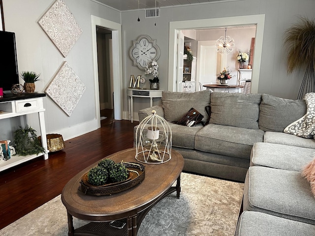 living room with baseboards, wood finished floors, visible vents, and a notable chandelier