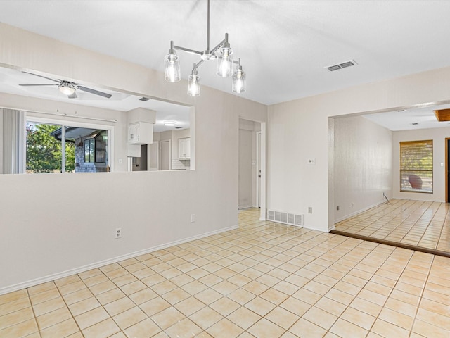 empty room with baseboards, light tile patterned flooring, visible vents, and a ceiling fan