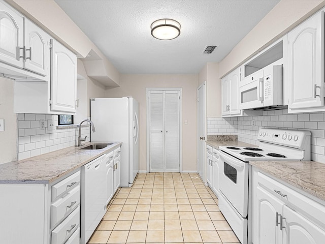 kitchen with visible vents, white appliances, a sink, and white cabinetry