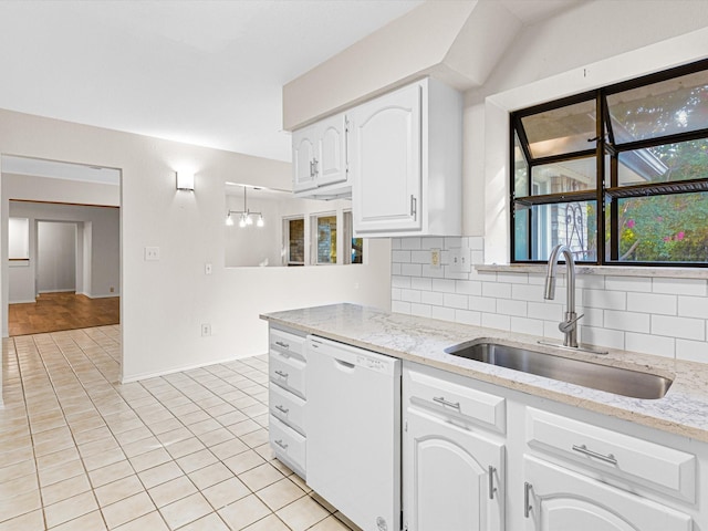 kitchen featuring light tile patterned floors, a sink, white cabinets, dishwasher, and tasteful backsplash