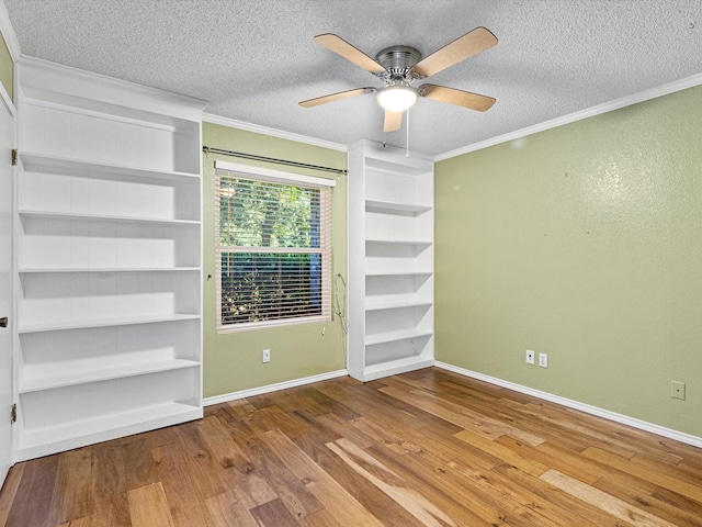 spare room featuring ornamental molding, a textured ceiling, baseboards, and wood finished floors