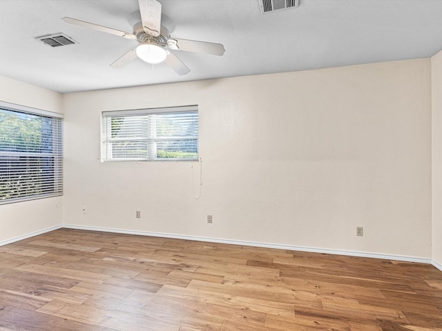 spare room featuring a wealth of natural light, ceiling fan, light wood-style flooring, and visible vents