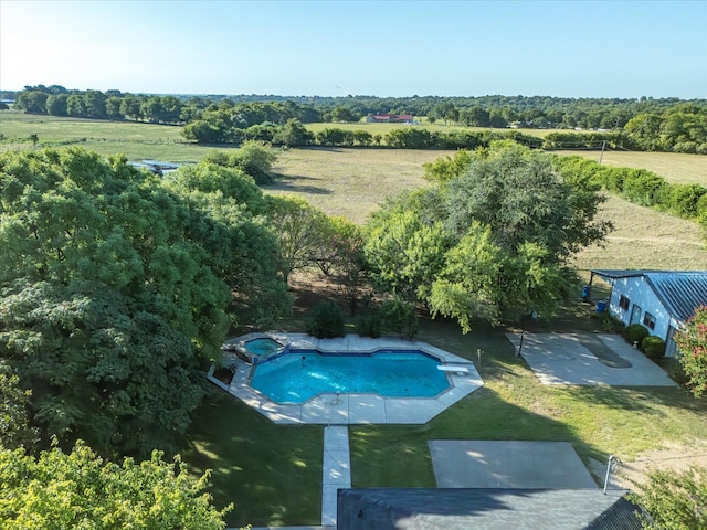 view of pool featuring a yard, a pool with connected hot tub, a rural view, and a patio