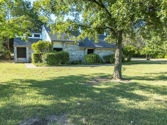 view of front of house featuring a front lawn, roof with shingles, and brick siding