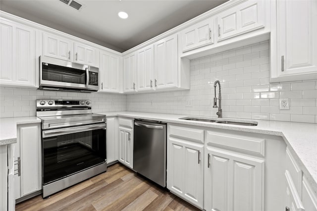 kitchen featuring stainless steel appliances, white cabinetry, a sink, and visible vents