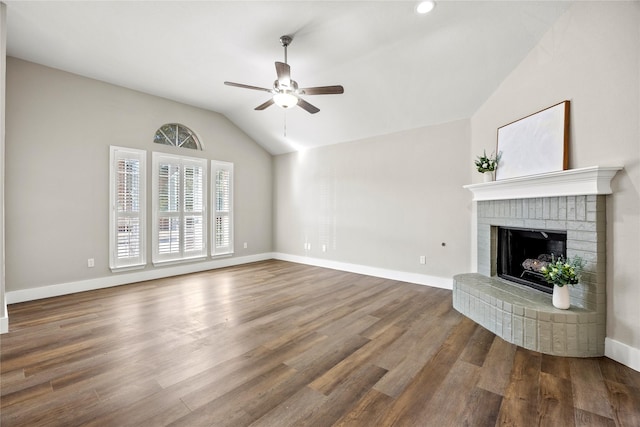 unfurnished living room featuring a fireplace, lofted ceiling, a ceiling fan, wood finished floors, and baseboards